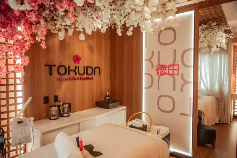 Recepção do Tokuda Head SPA com o logotipo na parede e flores de cerejeira